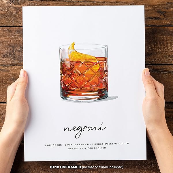 A woman is holding a piece of Negroni Cocktail Wall Art in both hands.
